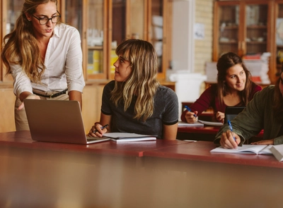 Woman teacher guiding students in classroom.