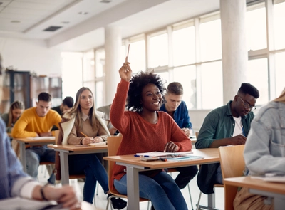 Young woman raising hand in a well-lit classroom.