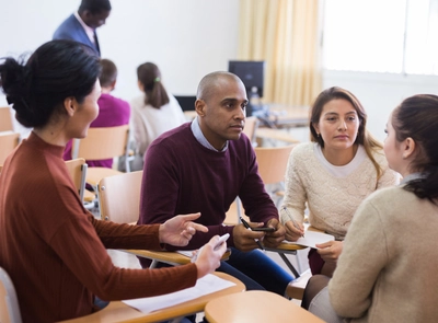 People sitting in desks in a circle talking