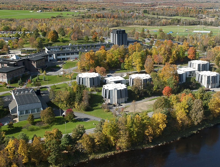 college campus spread out next to a river with many trees that are changing leaf colors for fall