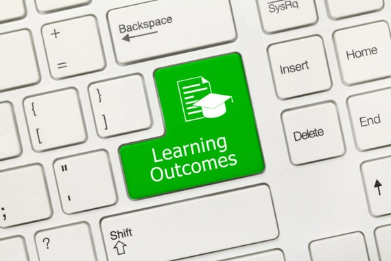 Close-up of key on keyboard. It's green and says "learning outcomes" with an icon of a graduation cap and a document on it