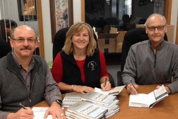 Authors of Leadership Foundations, Olin O. Oedekoven, Deborah Robbins, and John Lavrenz signing books