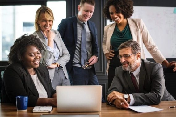 A group of business professionals working at a laptop